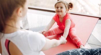 Woman in a sportswear. Mother with little daughter. Family are engaged in gymnastics in a gym