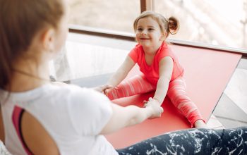 Woman in a sportswear. Mother with little daughter. Family are engaged in gymnastics in a gym